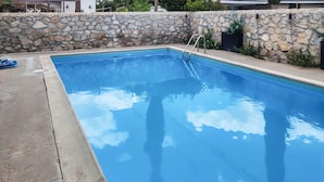 Una piscina rectangular con un muro de piedra y una escalera de metal.