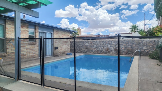 Una piscina con un muro de piedra y una valla de metal.