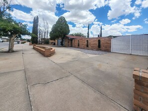 Zona residencial con camino pavimentado, edificios de ladrillo y entrada protegida por una reja.
