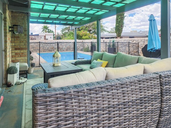 Un espacio de estar al aire libre cubierto, con una piscina al fondo.