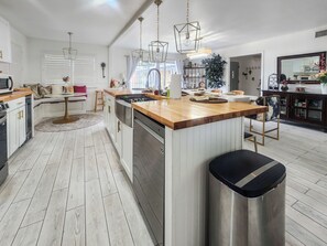 Una cocina moderna con una isla central, electrodomésticos de acero inoxidable e iluminación colgante.