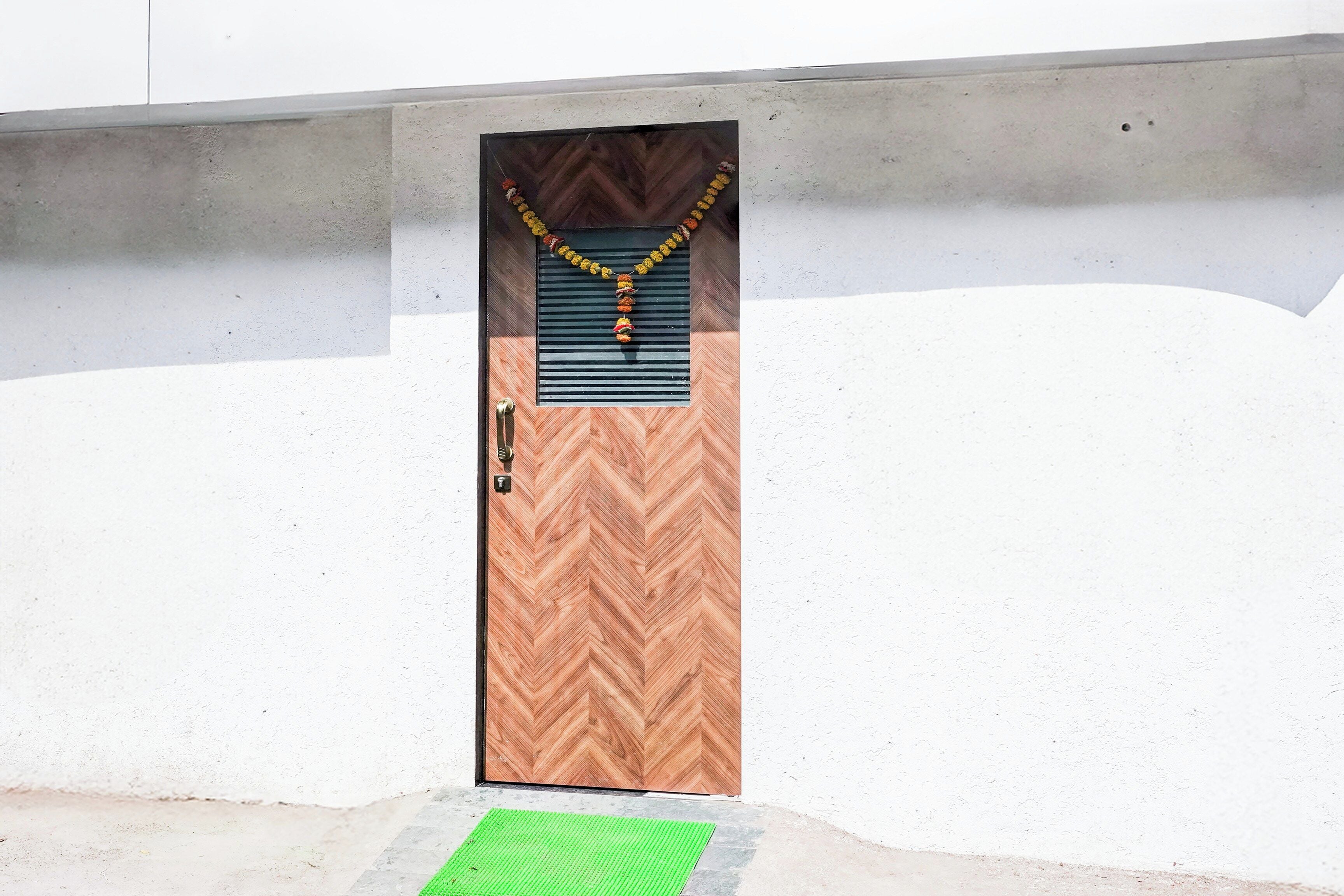Una puerta con un panel de diseño en zigzag, un picaporte metálico y un felpudo verde en la entrada.