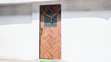 Una puerta con un panel de diseño en zigzag, un picaporte metálico y un felpudo verde en la entrada.