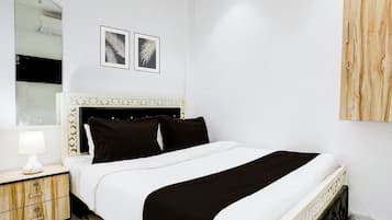 Un dormitorio con una cama, una mesita de noche, una lámpara, un espejo y dos cuadros en la pared.