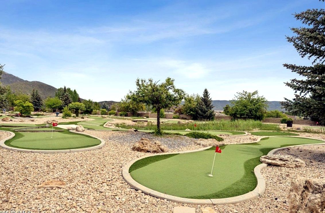 Un parcours de minigolf comportant plusieurs trous, entouré d’arbres et avec une chaîne de montagnes en arrière-plan.