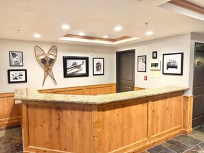 A reception area with a wooden counter, framed photographs on the wall, and a ceiling with recessed lighting.