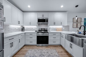 A modern kitchen with white cabinetry, stainless steel appliances, and a patterned rug.
