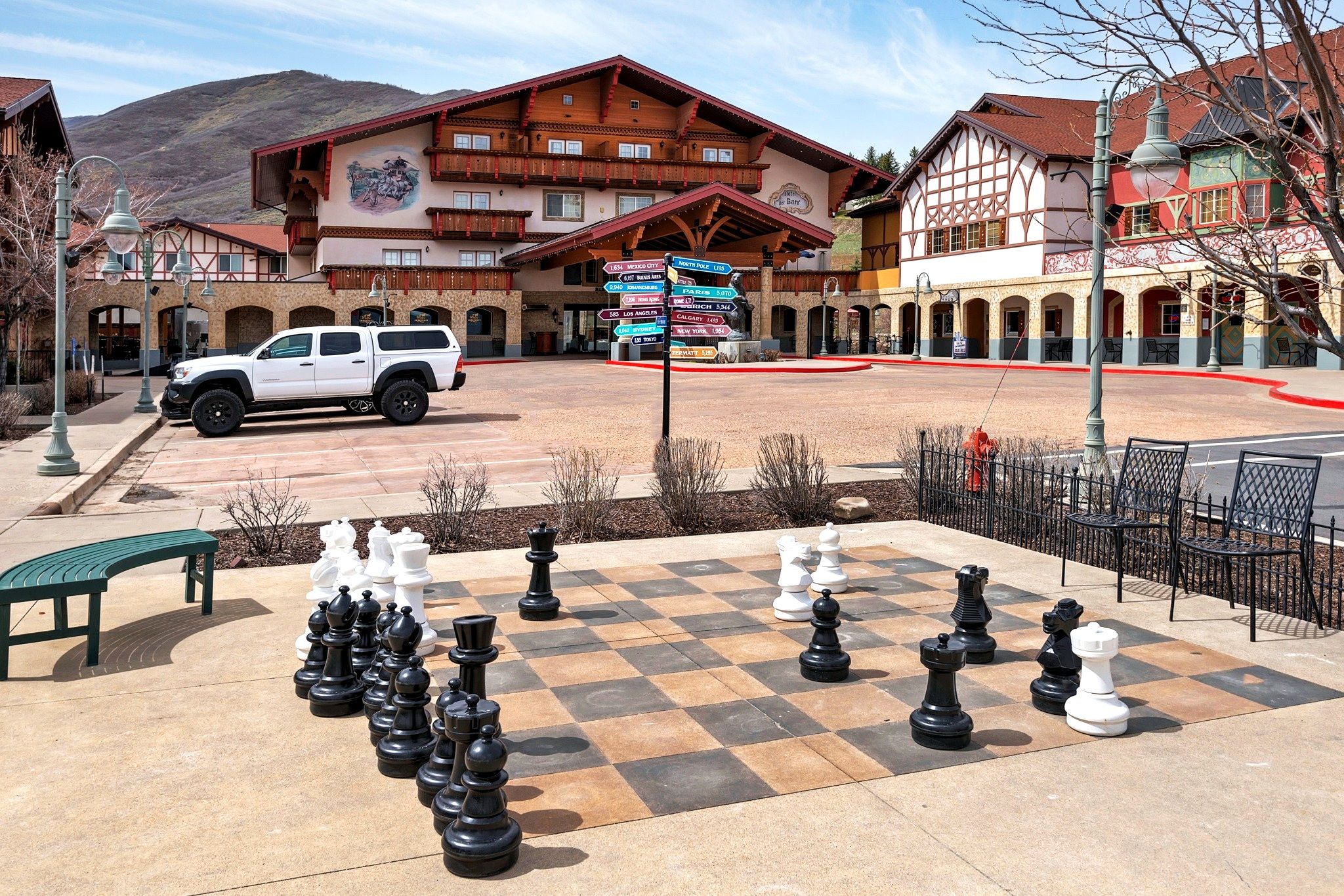 A hotel with a large outdoor chess set and a white pickup truck parked in front.