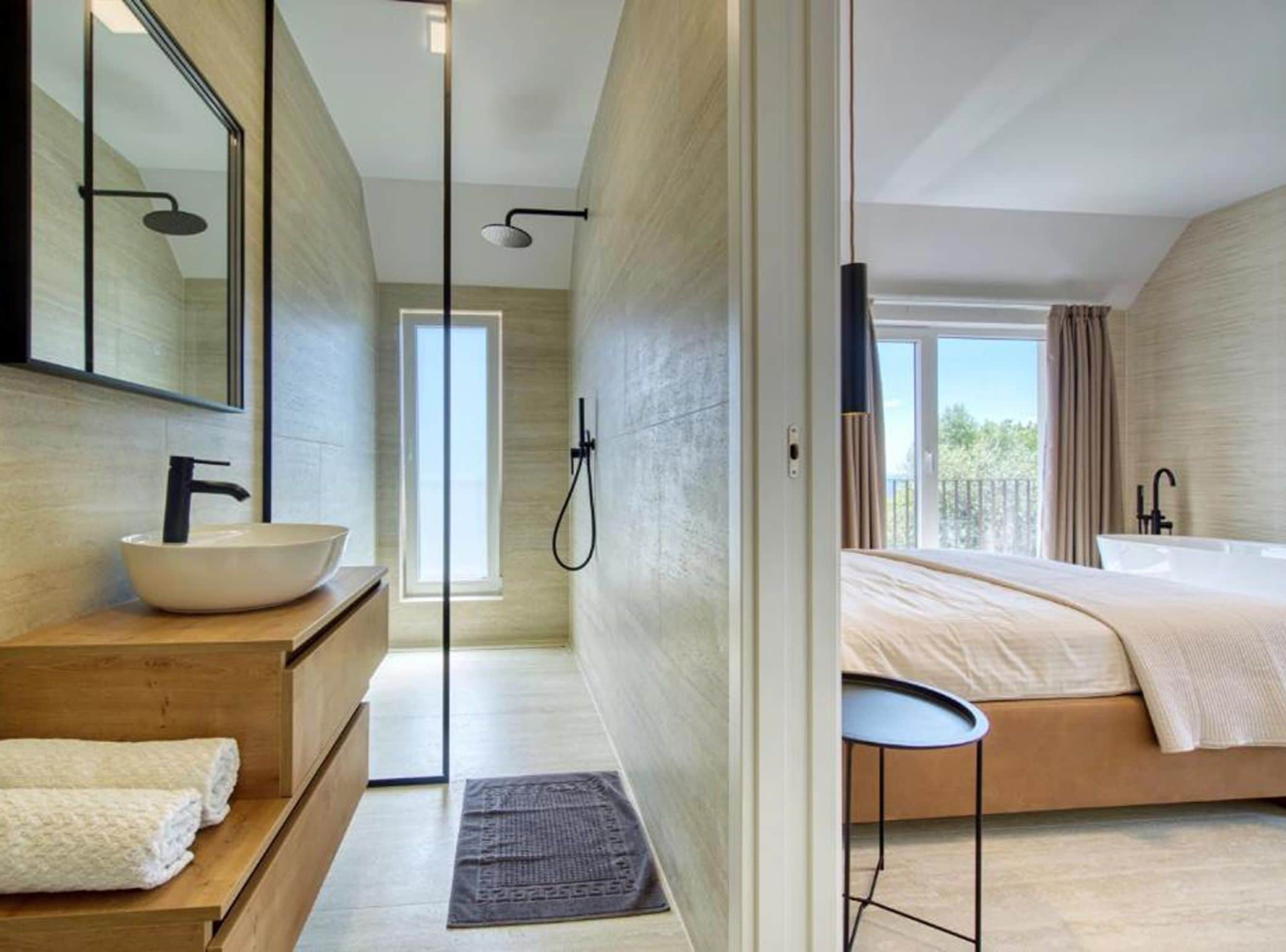 A modern bathroom with a large mirror, a white basin, and a shower.
