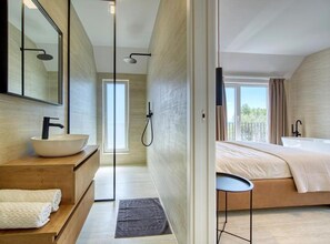 A modern bathroom with a large mirror, a white basin, and a shower.