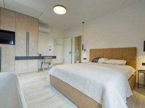 A modern bedroom with a large bed, a desk, and a television.