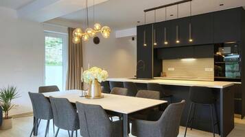 Una cocina moderna con una isla central, muebles oscuros y una zona de comedor con mesa y sillas.