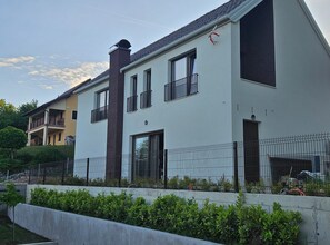 Ein modernes Wohnhaus mit zwei Stockwerken, einem Balkon, einem Schornstein und einem Metallzaun.