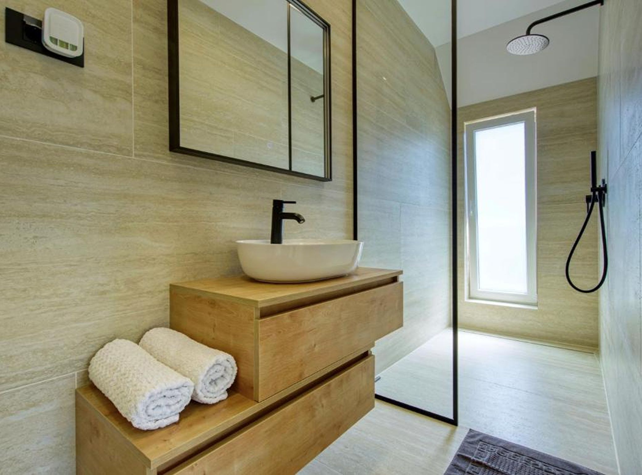 Une salle de bain moderne avec un meuble-lavabo en bois, un lavabo blanc et un grand miroir.