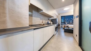A modern kitchen with a built-in oven, a washing machine, and a large window offering a city view. - ruilantingyuan (shenzhen)