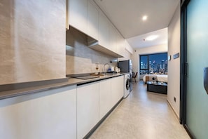 Eine moderne Küche mit Backofen, Waschmaschine und einem großen Fenster mit Blick auf die Stadt.