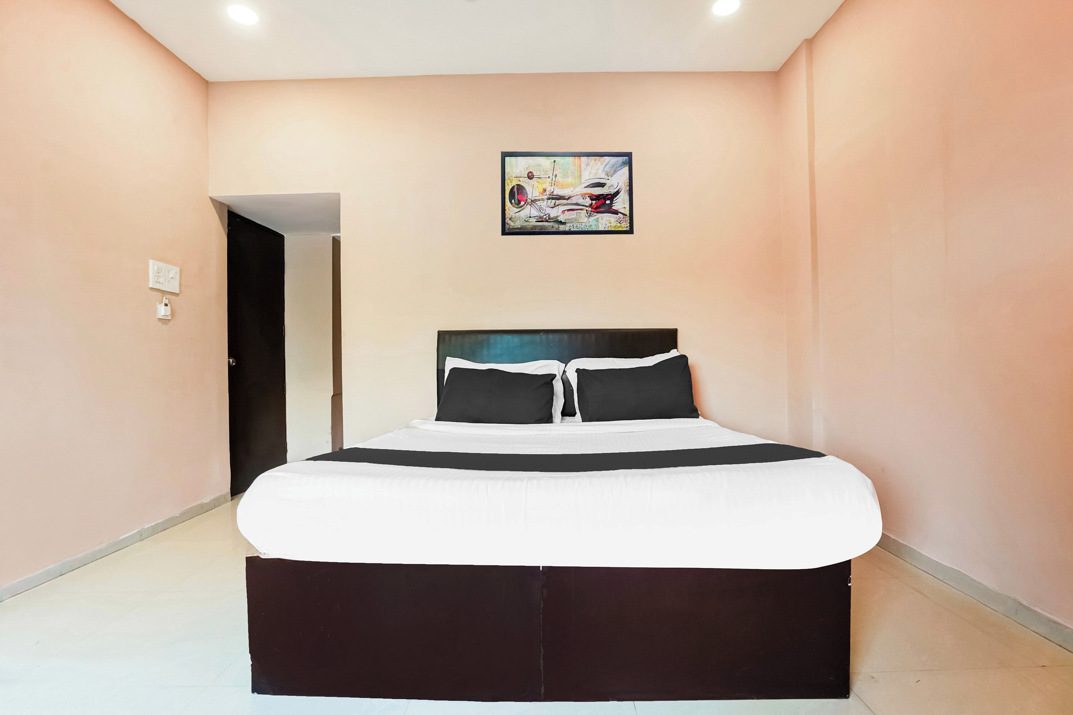 Un dormitorio con cama, una puerta y un cuadro en la pared.