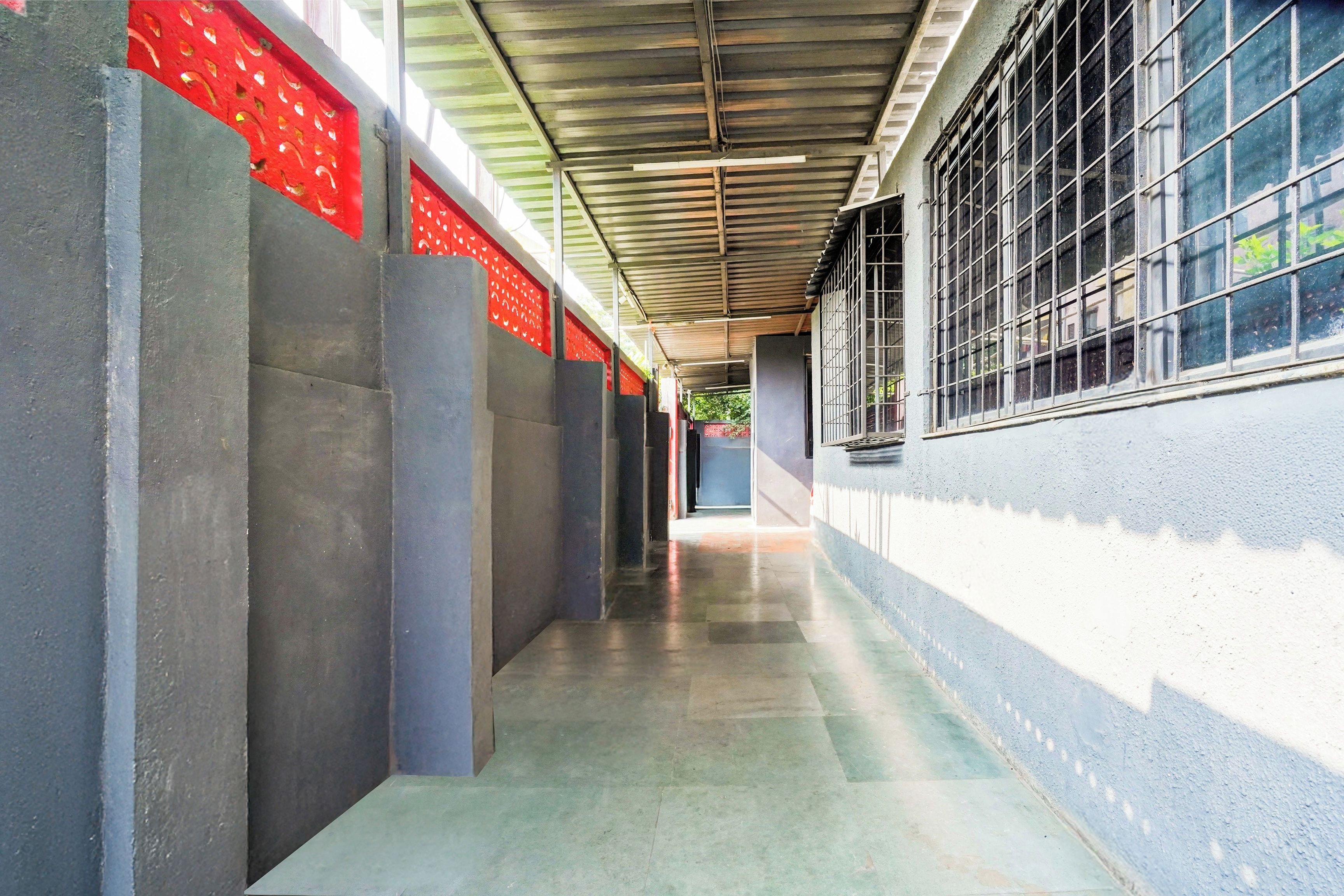 A corridor with a metal roof, concrete walls, and a tiled floor.