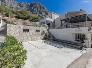 Ein modernes Gebäude mit Naturstein-Fassade, einer Treppe zum zweiten Stockwerk und freiem Blick auf eine gebirgige Landschaft.