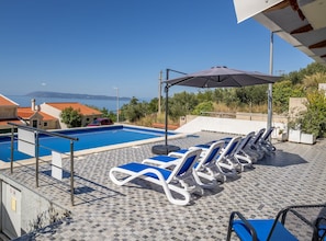 Ein Poolbereich mit Liegestühlen und Blick auf das Meer.