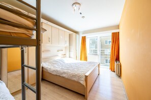 A bedroom with a bunk bed, a single bed, wooden wardrobe, and a radiator. - Apartment in Zeedijk With Sea View Terrace (Blankenberge)