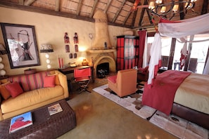 Une chambre de style traditionnel, dotée d’une cheminée, d’un canapé, d’un lit à baldaquin et de divers objets décoratifs.