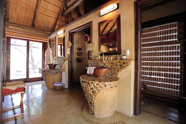 A bathroom with a stone sink, wooden beams, and a large mirror.