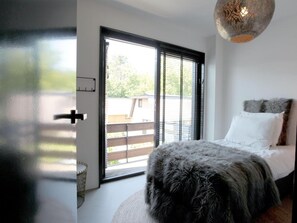 A bedroom with a bed, a window with blinds, and a view of the outside. - Villa With Sunny Garden in Schoorl (Schoorl)