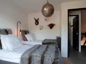 A bedroom with a bed, a hanging light fixture, and wall-mounted animal head decorations. - Villa With Sunny Garden in Schoorl (Schoorl)