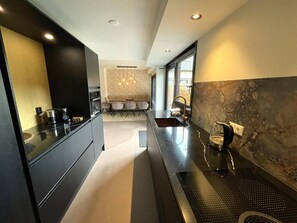 A modern kitchen with a central island, built-in appliances, and a dining area with a bench. - Villa With Sunny Garden in Schoorl (Schoorl)