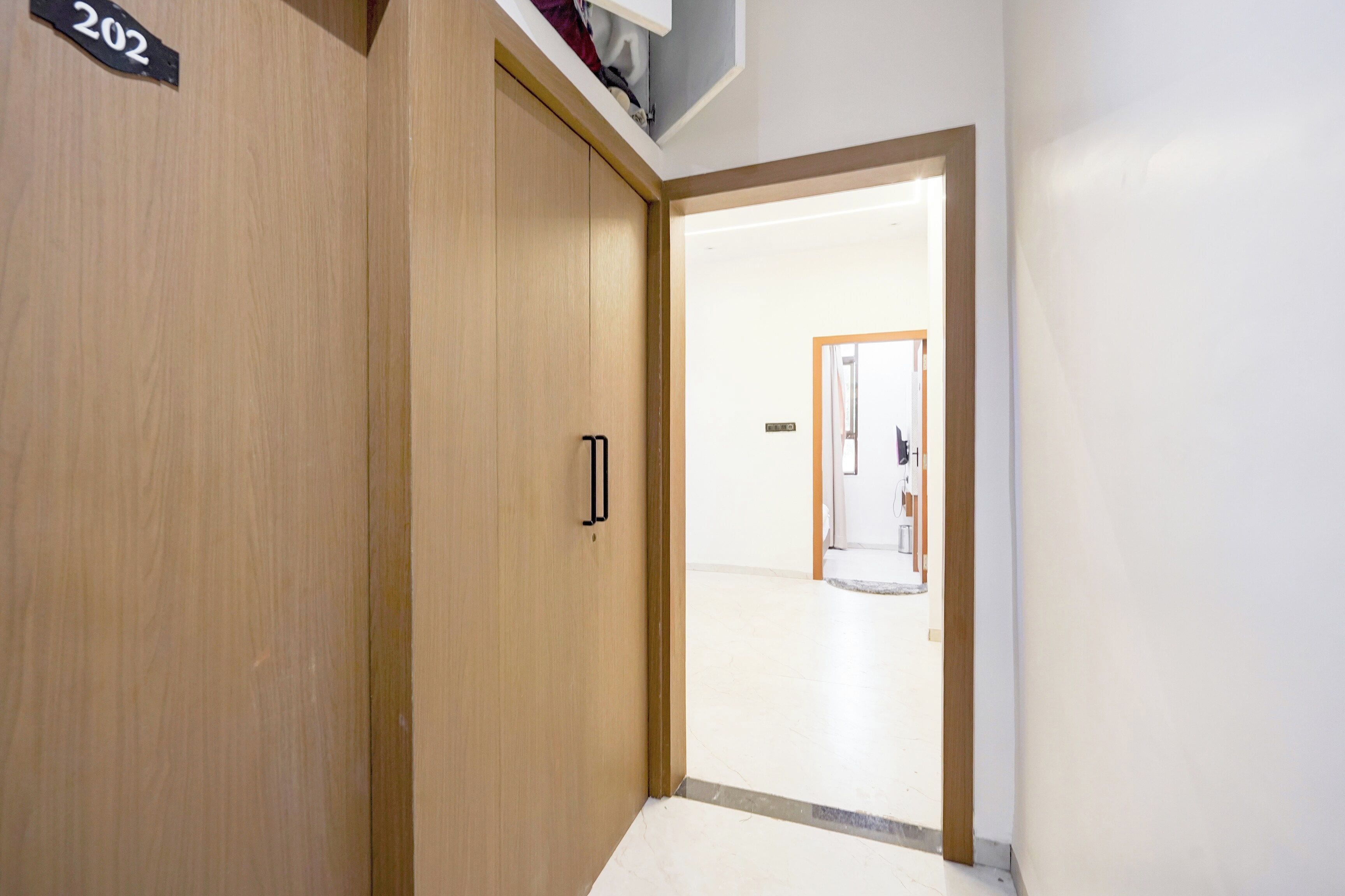 A hallway with a wooden door marked '202' and a white wall.