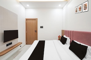 A modern bedroom with a bed, a TV, a door, and framed artwork on the wall. - Super Collection O Ujjain Central (Ujjain)