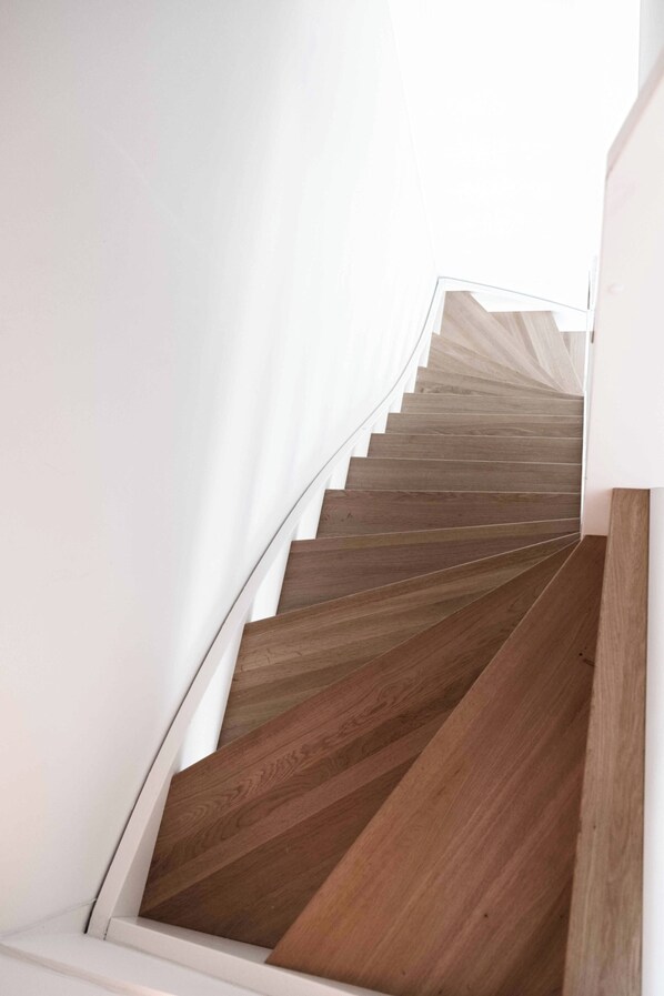 Una escalera con escalones de madera y paredes blancas.