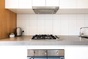 A modern kitchen with a gas stove, oven, and a kettle on the countertop. - Well Equipped 2BDR Apt in Southbank with Parking (Southbank)