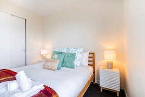 A hotel room with a bed, two bedside tables, a lamp on each table, and a door. - Well Equipped 2BDR Apt in Southbank with Parking (Southbank)