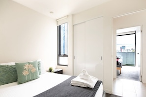 Een hotelkamer met een bed, een raam, een deur en uitzicht op de stad.