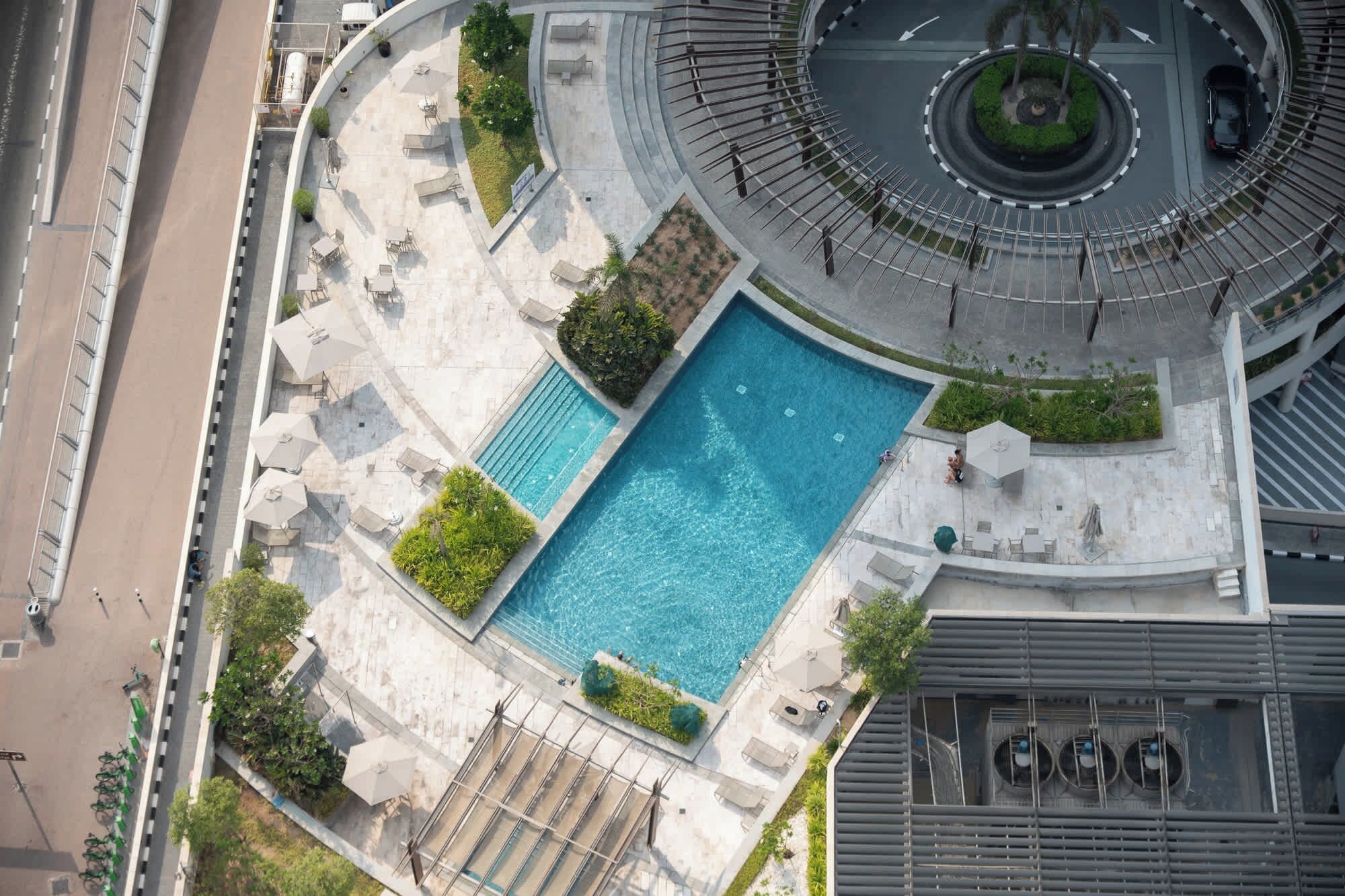 Ein Poolbereich auf dem Dach mit einem rechteckigen Pool, umgeben von Sitzgelegenheiten und Pflanzen.