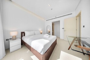 Une chambre à coucher moderne avec un grand lit, des lampes de chevet, une table en verre et un dressing.