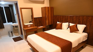 Quarto de hotel com cama, cabeceira de madeira, mesa de cabeceira, espelho e janela com cortinas.