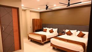 Quarto de hotel com duas camas, um guarda-roupa, um ventilador de teto e uma mesa de cabeceira.