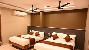 Quarto de hotel com duas camas, ventoinha no teto, aparelho de ar condicionado e design moderno.