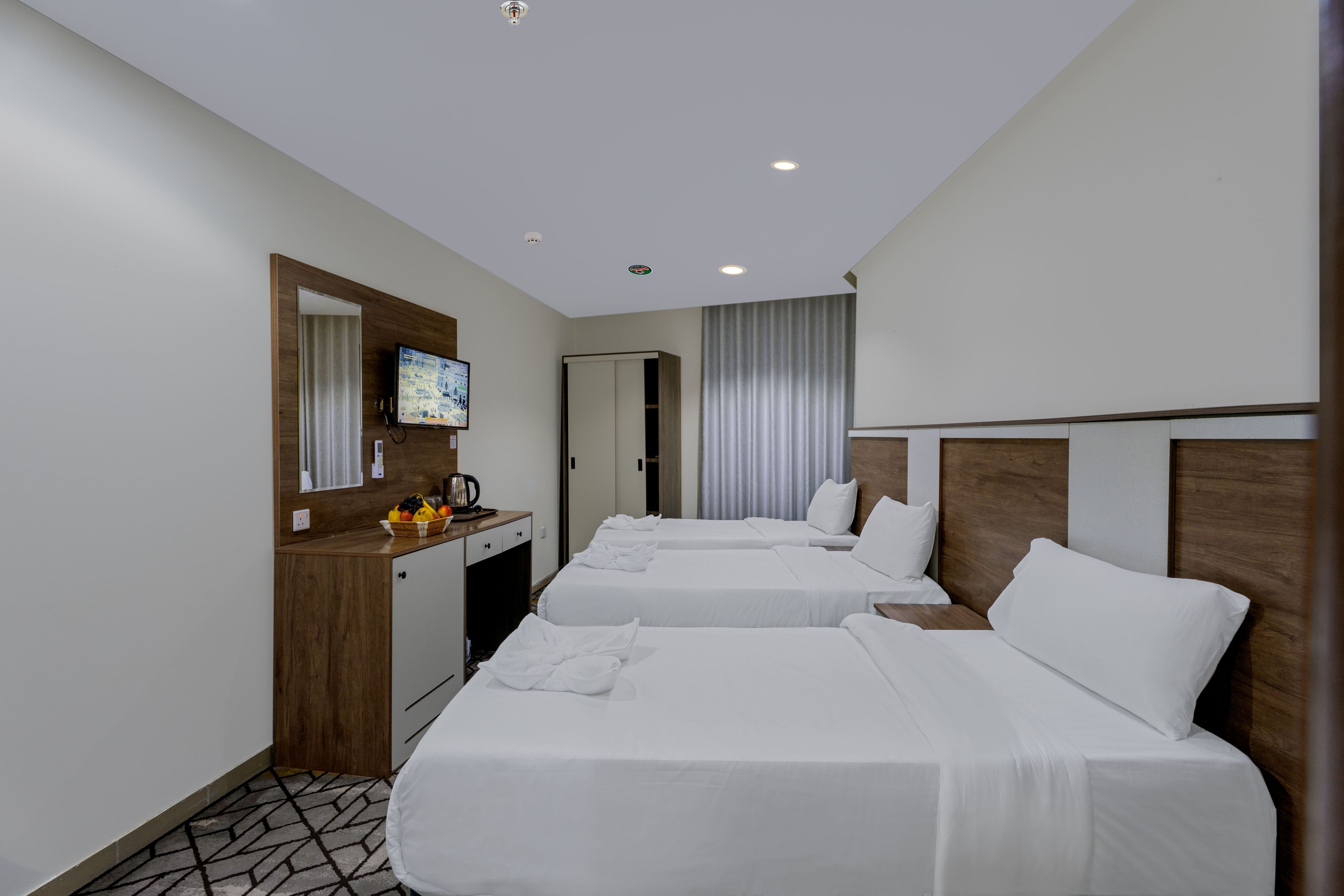 Ein Hotelzimmer mit zwei Betten, einem Schreibtisch, einem Fernseher und einem Badezimmer.