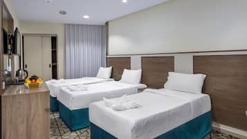 Une chambre d’hôtel avec deux lits, un coin cuisine, un miroir et un panier de fruits.