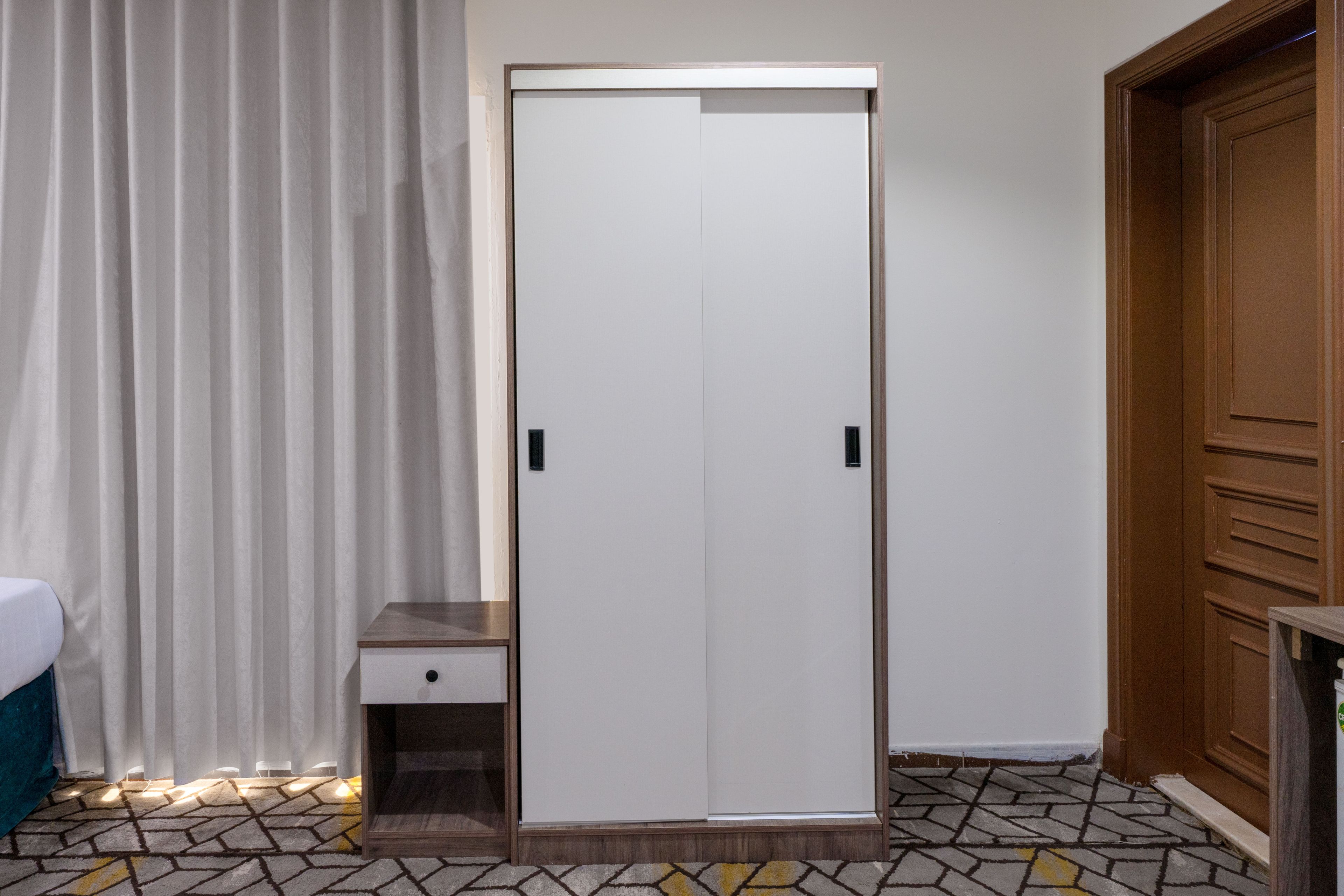 Ein Zimmer mit Schrank, Nachttisch und einem gemusterten Boden.