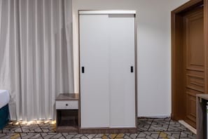 A room with a wardrobe, a bedside table, and a patterned floor. - ADDRESS AJYAD HOTEL (Makkah)