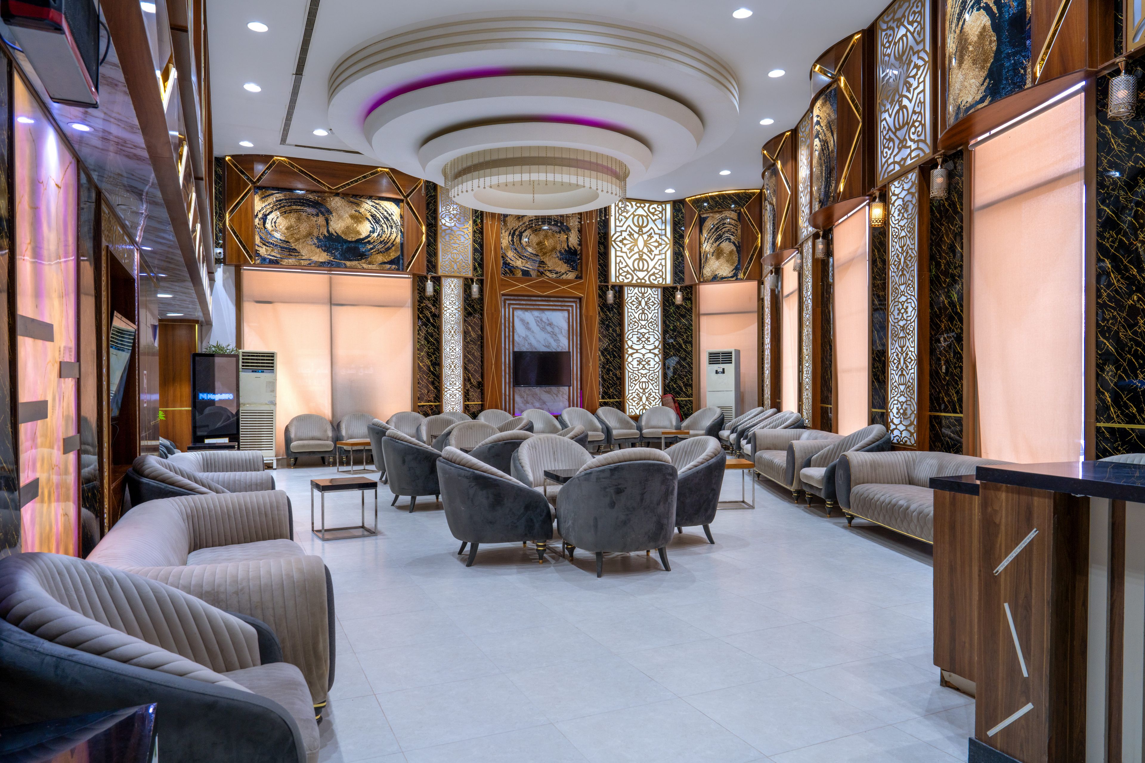 Un amplio salón con diversas opciones de asiento, incluyendo sofás y sillones, distribuidos en forma semicircular.