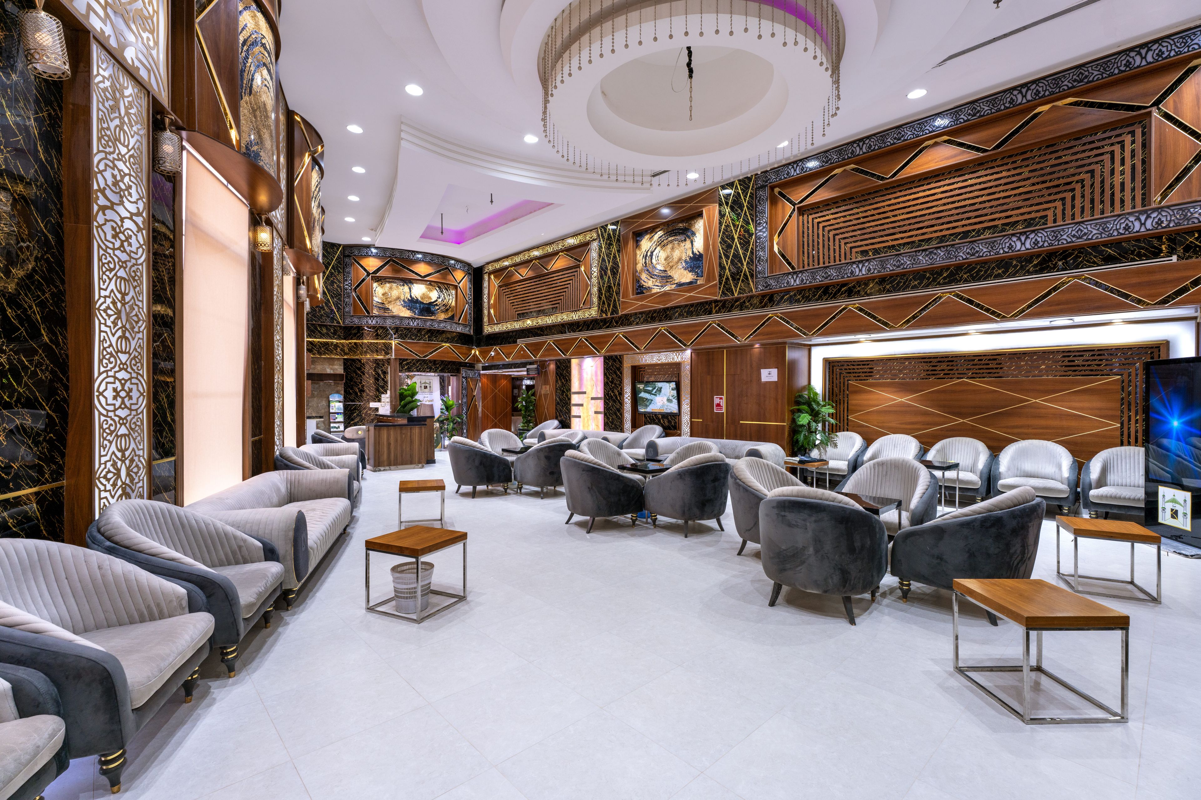 A spacious lobby with seating areas, a reception desk, and a large screen.