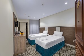Una habitación de hotel con dos camas, un escritorio con un hervidor y un espejo.