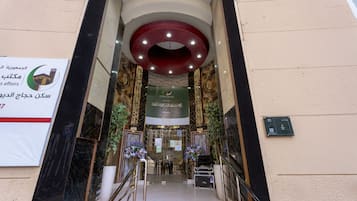 A hotel entrance with a reception desk, a staircase, and a sign indicating the hotel's name.