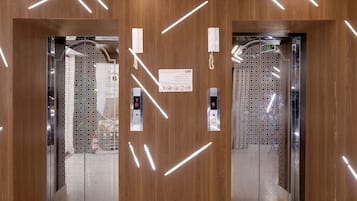 Interior de ascensor con paneles de madera e iluminación moderna.